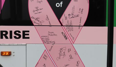 A pink ribbon with signatures on the side of an RTA bus
